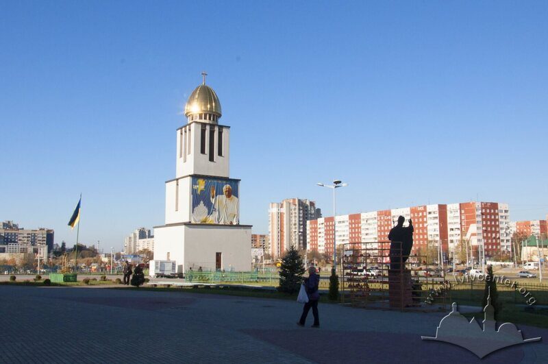 Просп. Червоної калини, 70. Дзвіниця церкви. На тлі справа - житлові будинки на просп. Червоної калини, 61 та 77