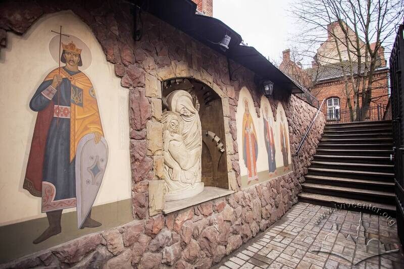Вул. Генерала Чупринки, 70. Підпірна стіна при вході на територію церкви і колишнього монастиря із розписами-зображеннями святих та скульптурним зображенням Діви Марії та Ісуса Христа